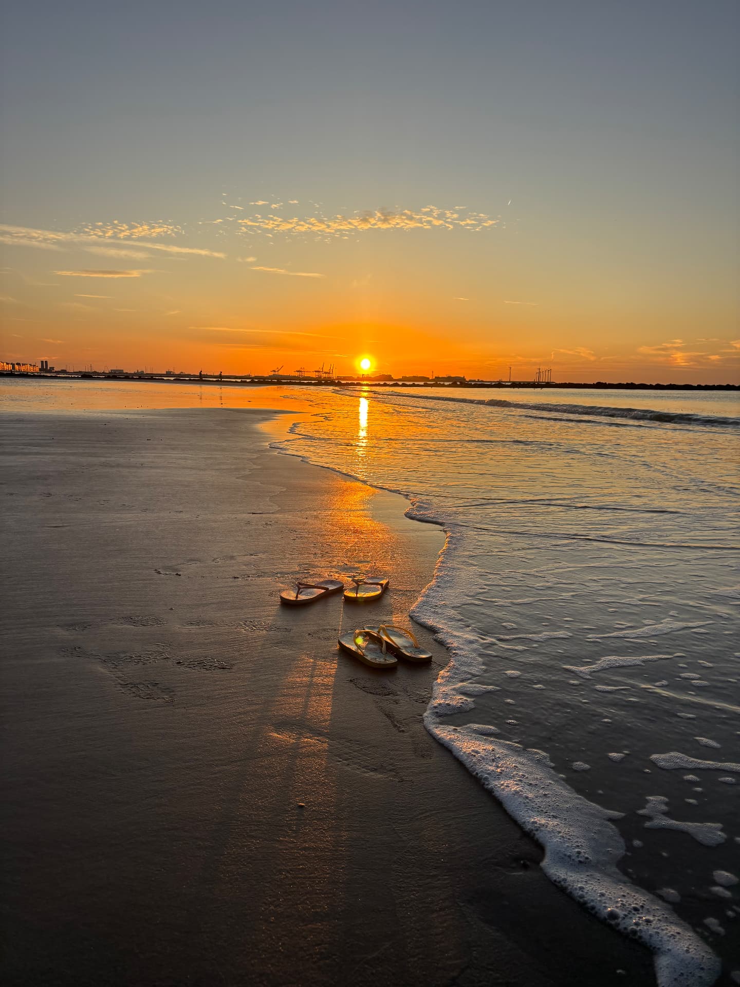 Zonsopgang aan zee met slippers op het strand